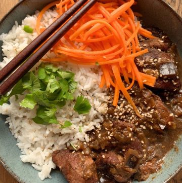 caramel pork served with rice, pickled carrots and sprinkled with coriander in a blue bowl
