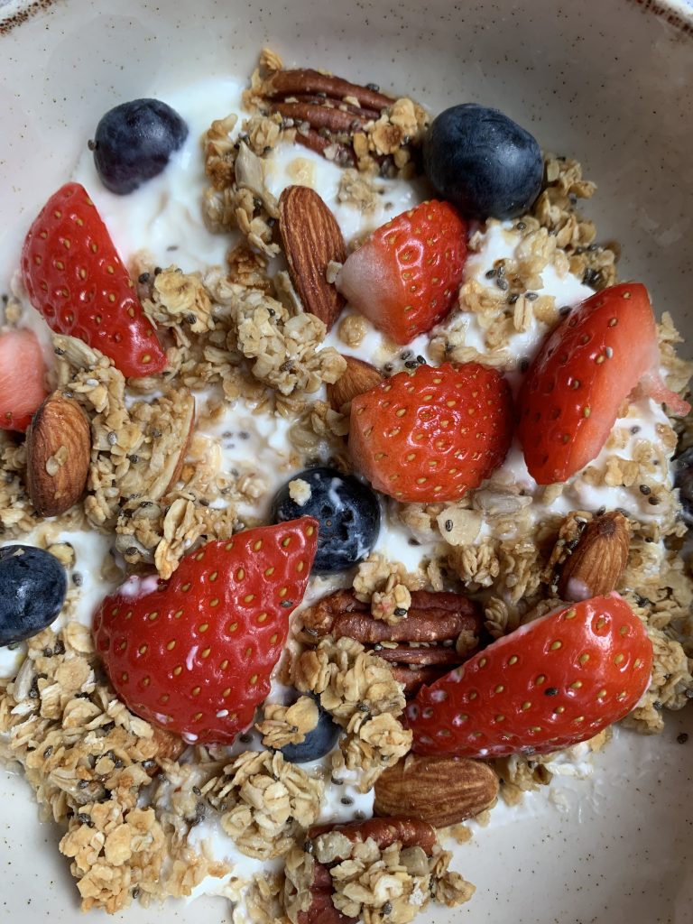 Close up homemade honey granola served with Greek Yoghurt and berries 