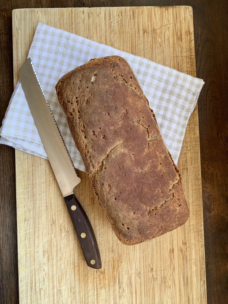 Whole gluten free buckwheat bread on a wooden board with a bread knife