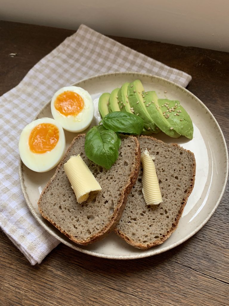 bread with butter on a plate with avocado and egg