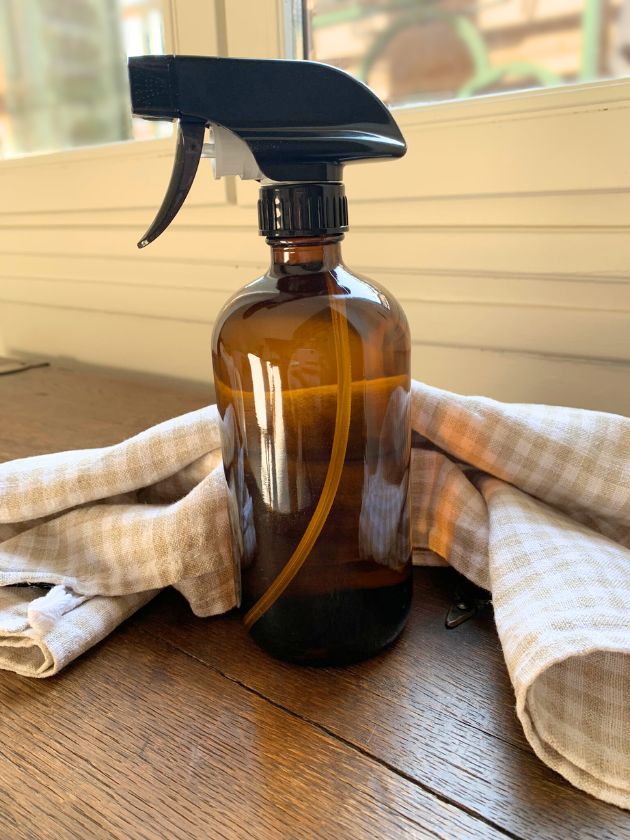 Spray bottle containing homemade cleaner using vinegar and essential oils