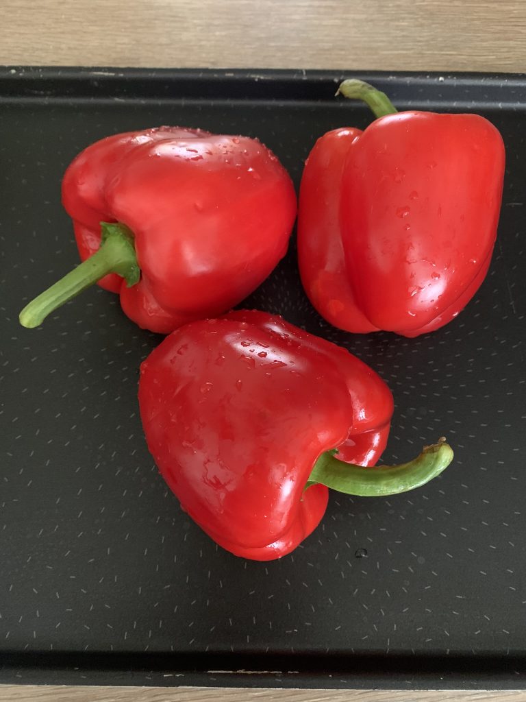 3 red peppers on a baking tray