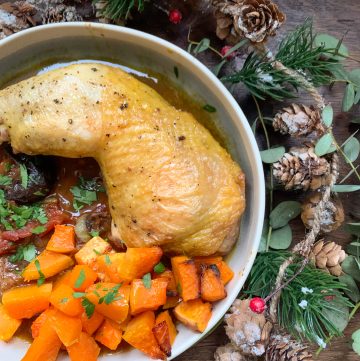 Christmas chicken tagine with prunes and apricots served with roasted butternut squash on a small plate surrounded by a festive garland
