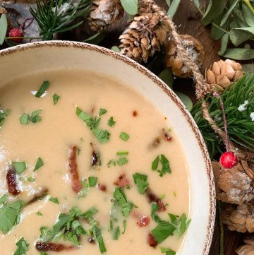 Creamy white bean soup with roasted garlic and bacon on a wooden table with christmas garland