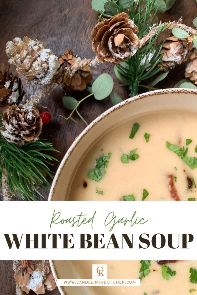 Creamy white bean soup with roasted garlic and bacon on a wooden table with christmas garland 