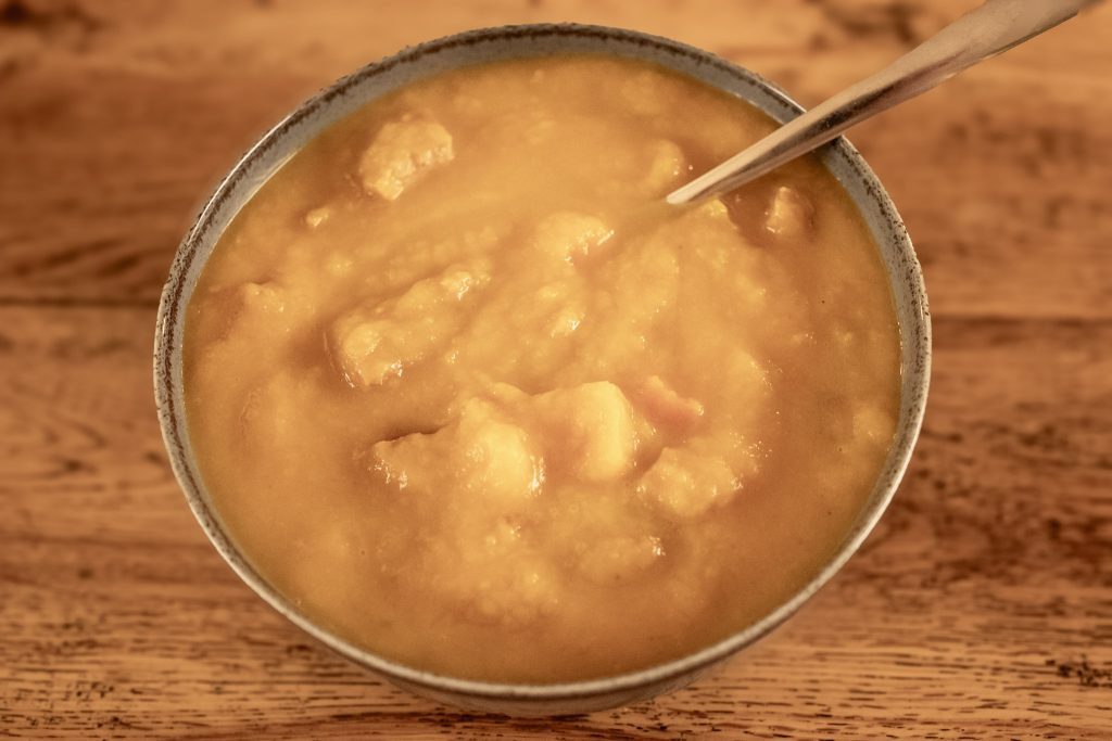 Cosy sausage and vegetable soup in a bowl with a spoon