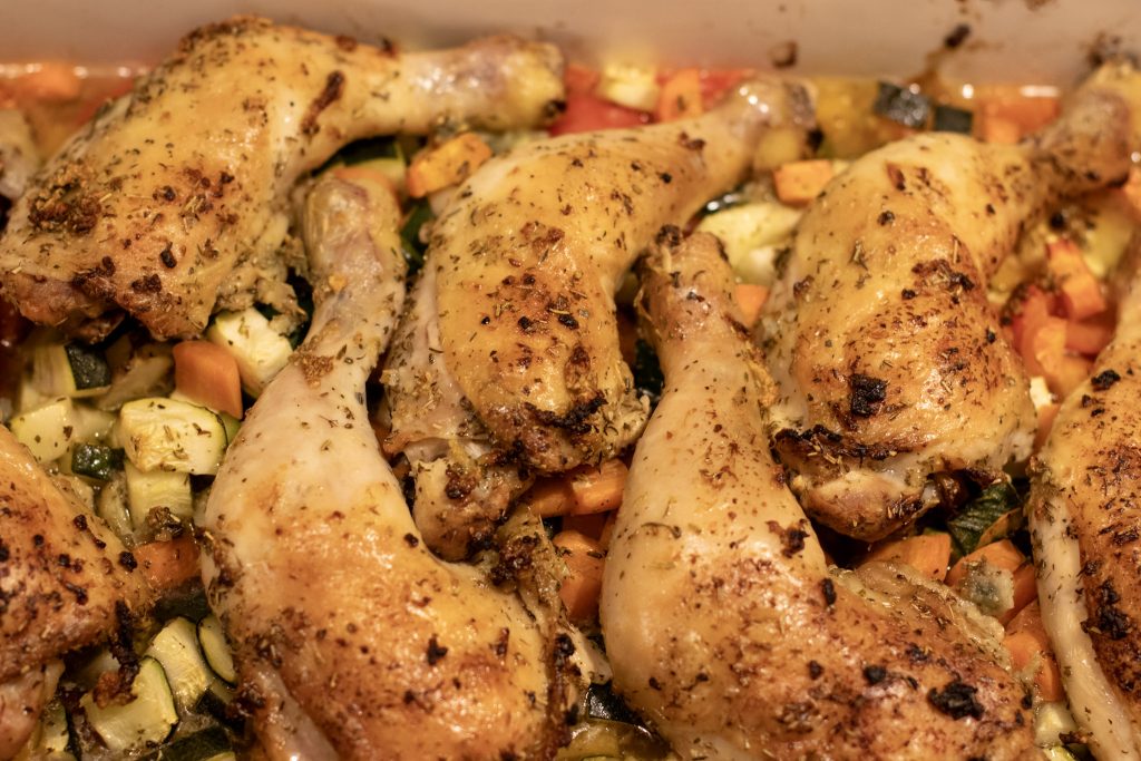 close up of roasted chicken legs and vegetables