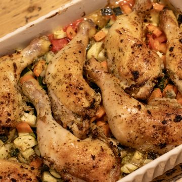 Sheet Pan Lemon and Garlic Chicken with Veggies in a white ceramic dish