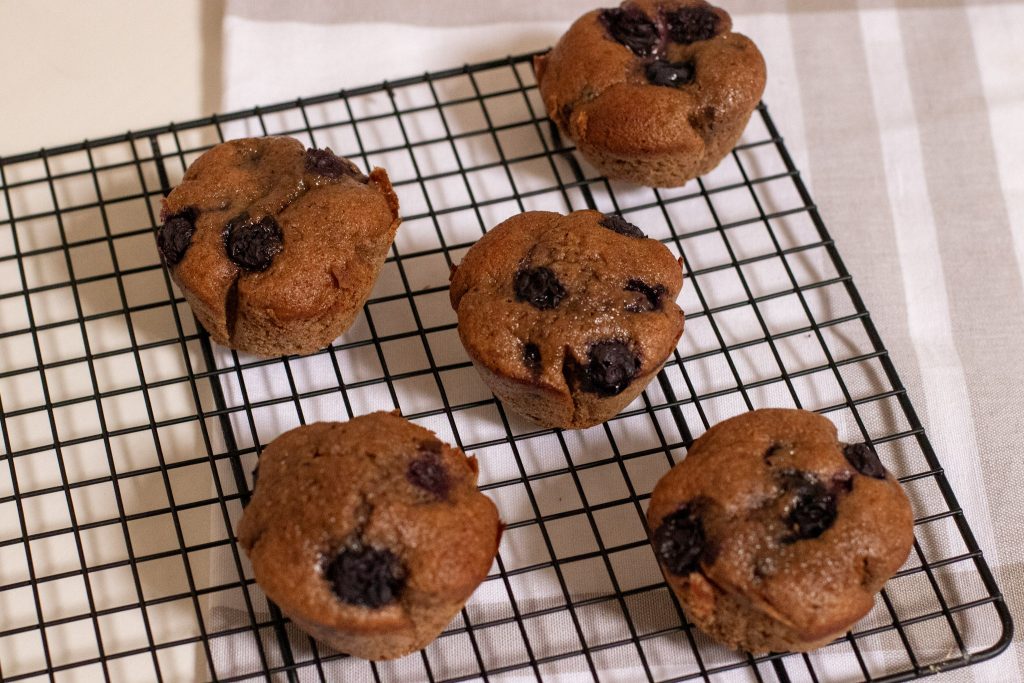5 Dairy Free Whole Wheat Blueberry Muffins on a black wire rack