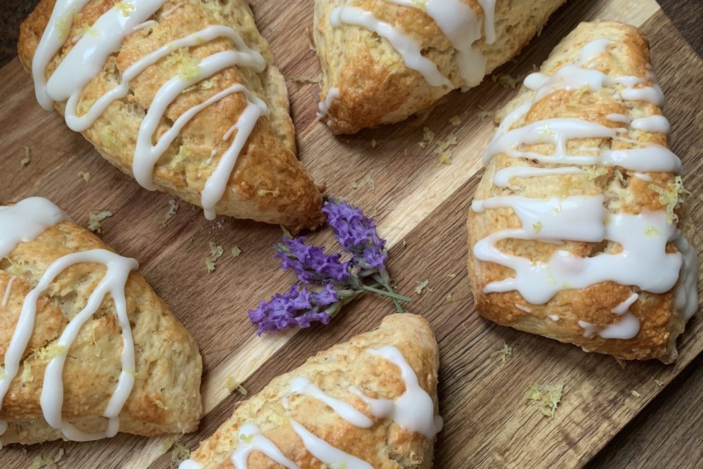 Lemon scones with icing drizzled on a wooden board with some lavender