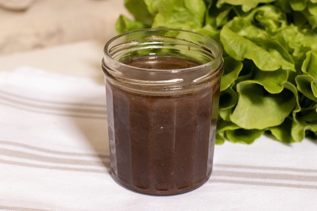 Asian Style Balsamic Salad Dressing in a jam jar with a lettuce in back ground 