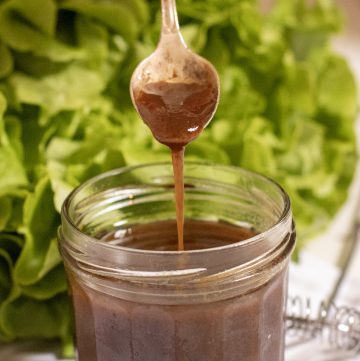 Asian-Style Balsamic Salad Dressing in a jam jar with a spoon drizzling