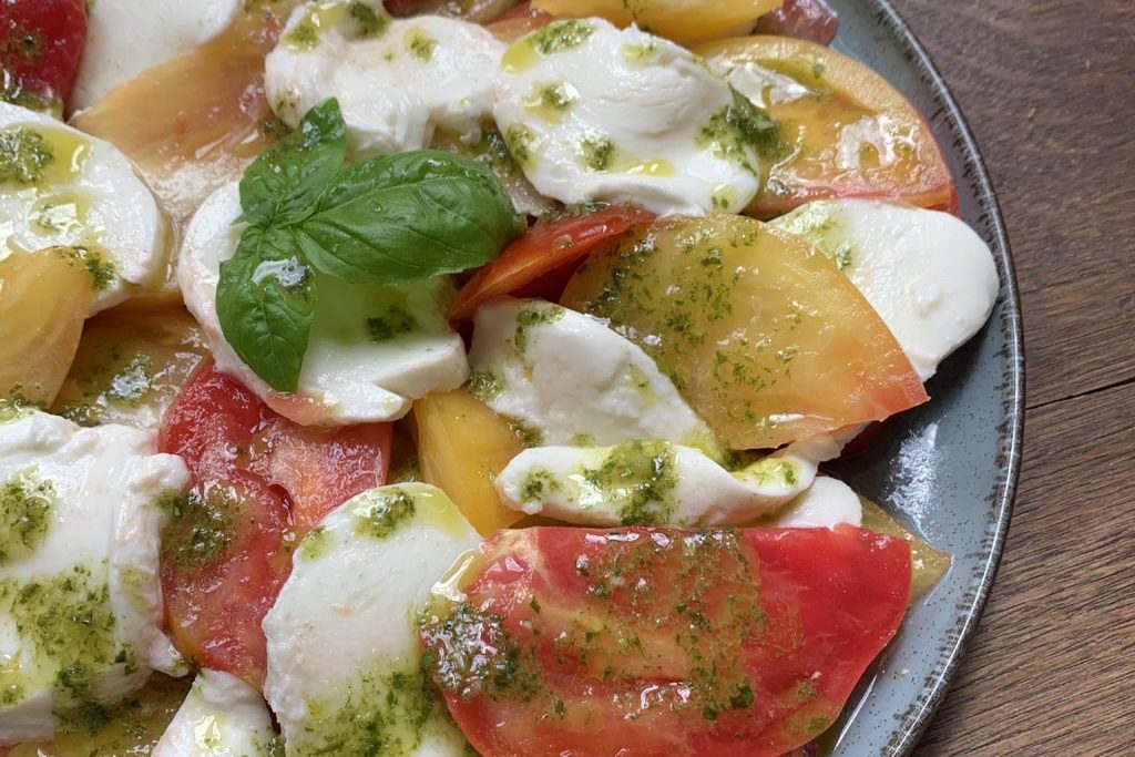 Tomato and mozzarella salad with basil oil on a blue plate