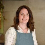 Sarah in her kitchen with a blue apron on